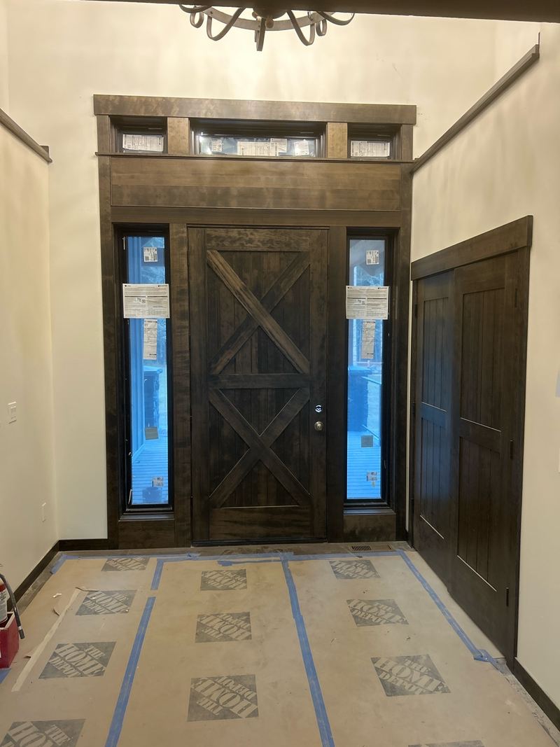 Dark-stained X-brace front door with sidelights and transom windows